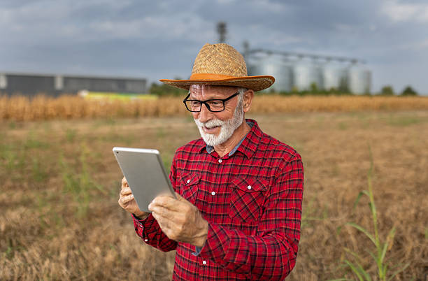 istock Satisfied farmer looking at tablet in front of silos in field 2204345286
