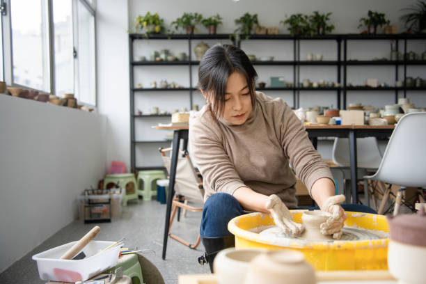 istock Confident craftsperson molding clay on pottery wheel at workshop 2204345606