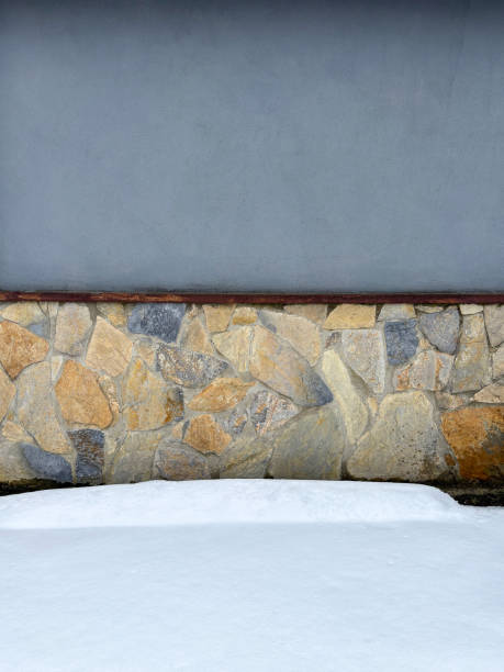 Stone and concrete wall with snow floor. Front view outdoor wall and floor background with copy space