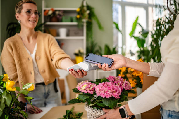 istock Customer completing purchase using contactless payment technology at a flower shop with fresh blooms all around 2204345772