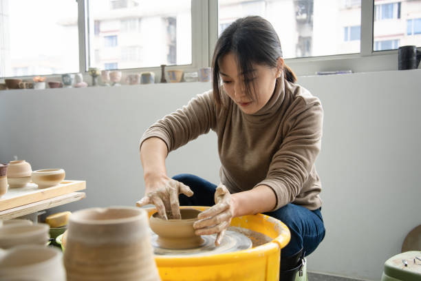 istock Confident craftsperson molding clay on pottery wheel at workshop 2204346376