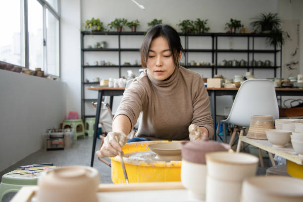 istock Confident craftsperson molding clay on pottery wheel at workshop 2204347377