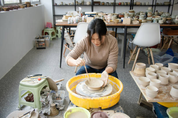 istock Confident craftsperson molding clay on pottery wheel at workshop 2204347379