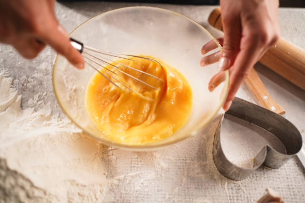 istock whisking smooth eggs in a glass bowl, preparing dough for baking. The scene captures the texture and motion in a cozy kitchen setting 2204347586