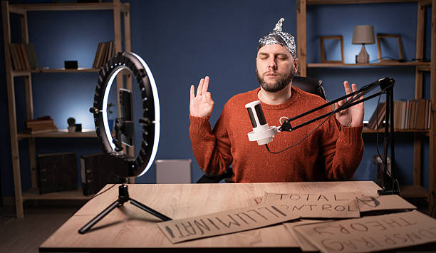 istock Crazy conspiracy theorist blogger streaming live at home using smartphone and ring light, meditation has zen sitting at the table 2204347588