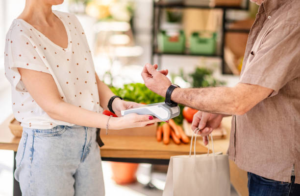 istock Modern grocery shopping experience with contactless payment method between two young adults in a fresh market 2204347628