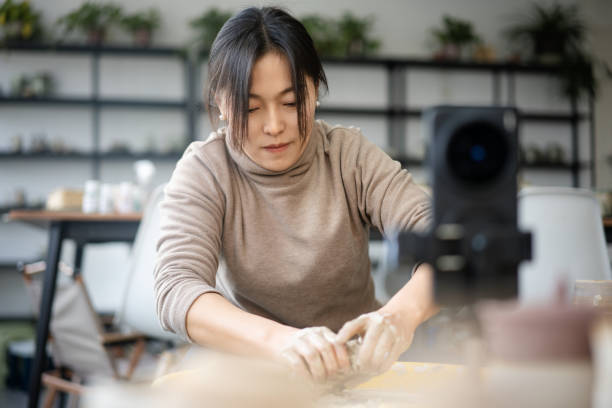 Confident craftsperson molding clay on pottery wheel at workshop