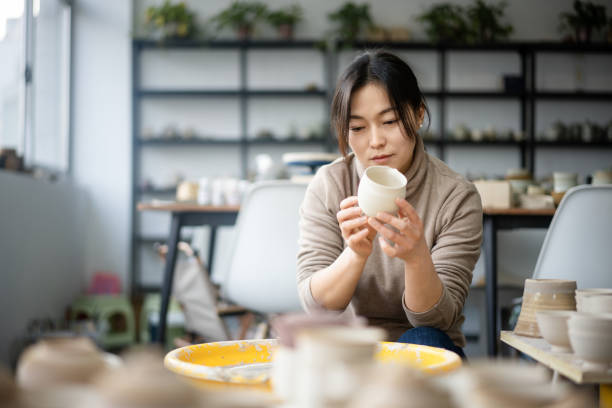 istock Confident craftsperson molding clay on pottery wheel at workshop 2204349742