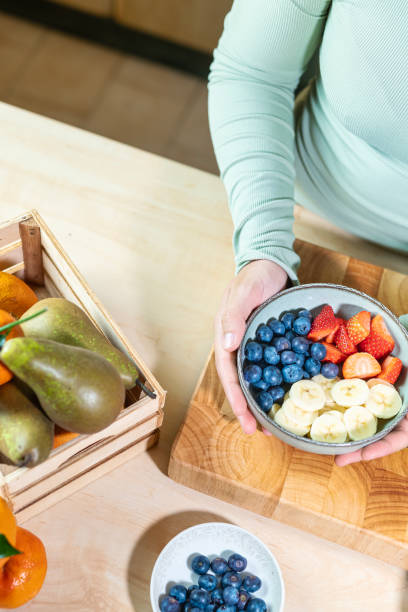 istock Hands presenting a bowl of fresh fruit in the kitchen (overhead shot). 2204350005