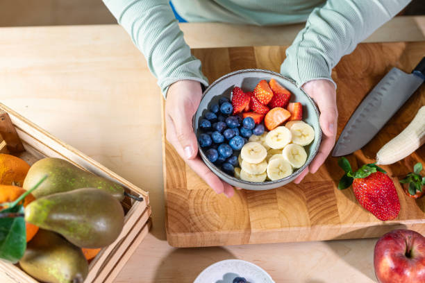 istock Hands holding a bowl of fresh fruit with cutting board and knife. 2204350013