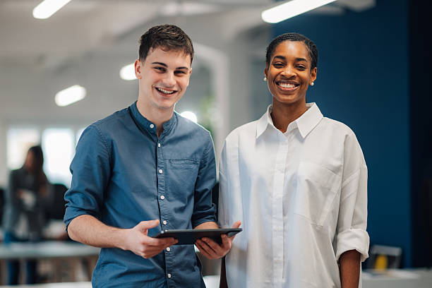 istock Smiling business colleagues holding digital tablet in modern office 2204354181