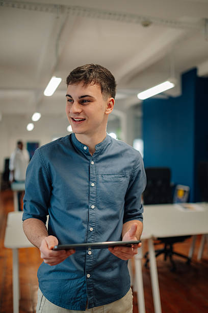 istock Young man holding tablet and smiling in modern office space 2204354246