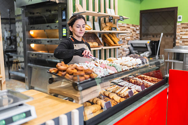 istock Baker arranging pastries in display case at bakery shop 2204354504