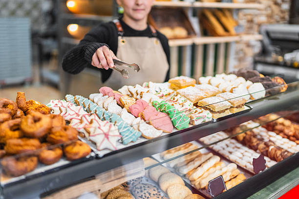 Pastry chef arranging christmas cookies in bakery display case