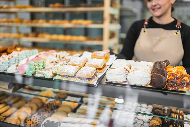 istock Smiling pastry chef arranging delicious pastries in display case 2204354533