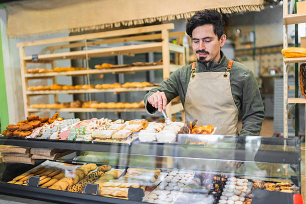 istock Baker arranging pastries in display case at bakery shop 2204354579