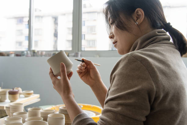 istock Asian female ceramic artist is carving on the cup 2204355235