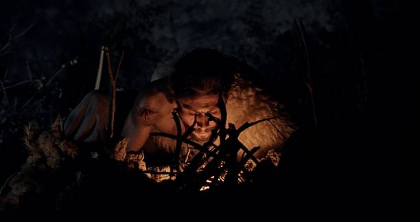 istock Cave Dweller Lighting a Fire at Night in a Primitive Setting Surrounded by Darkness and Nature 2204355251