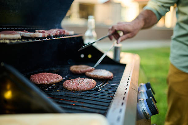 istock Man grilling hamburgers and steaks on backyard grill 2204356780