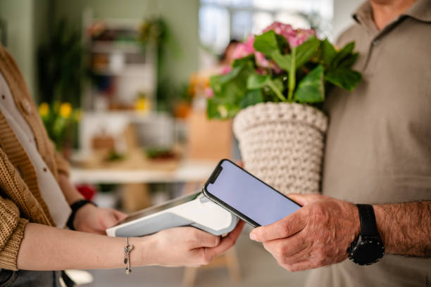 istock Paying for flowers using mobile technology at a flower shop with a contactless payment system 2204357342
