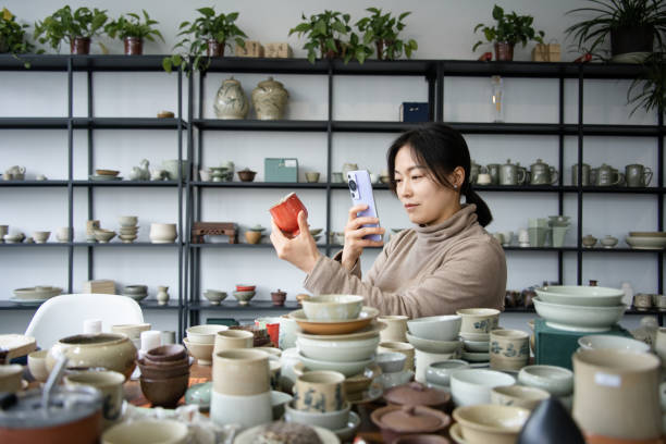 istock Confident craftsperson take picture with smart phone while molding clay on pottery wheel at workshop 2204357542