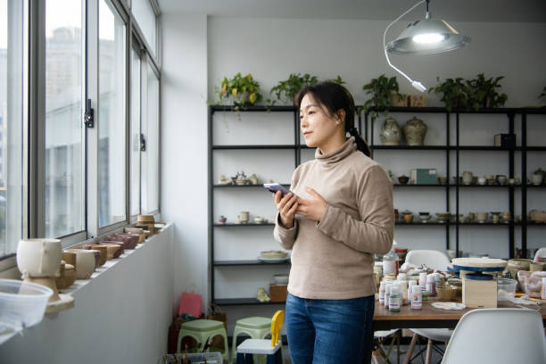 istock Asian female ceramic artist is using a mobile phone in the studio 2204358471