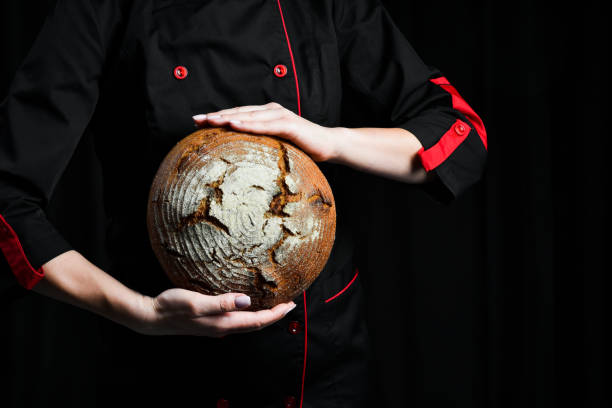istock Female hands hold Fresh Sourdough Bread on black background. Top view. 2204358847
