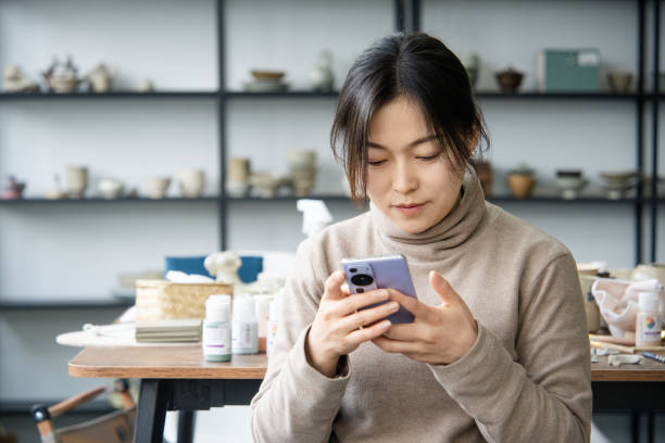 istock Asian female ceramic artist is using a mobile phone in the studio 2204359188