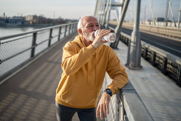 istock Senior man drinking water after exercising on a bridge 2204361009