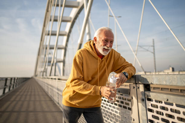 istock Senior man drinking water after exercising on a bridge 2204361071