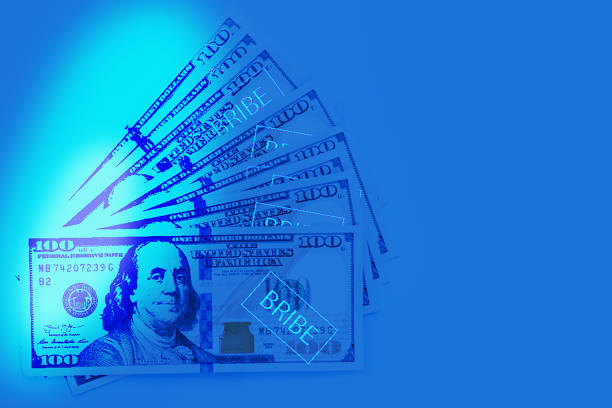 Corruption concept. US Dollar cash money in uv light on blue background
