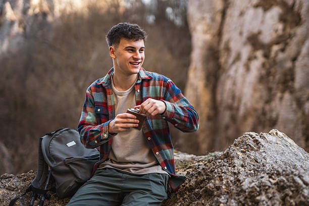 istock young man hiker sit on rock and drink alcohol from flask and enjoy 2204364327