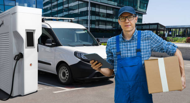 istock Delivery man in uniform with digital tablet next to electric van 2204365055