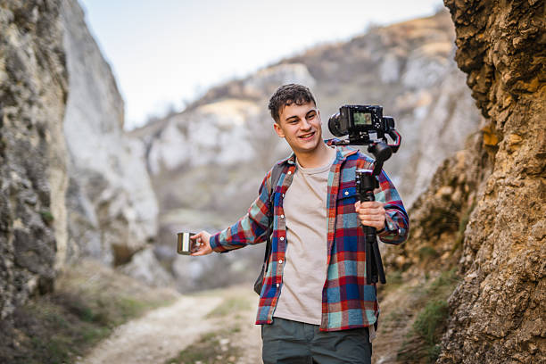istock Man hiker making video on camera with stabilizer show cup on footpath 2204365204