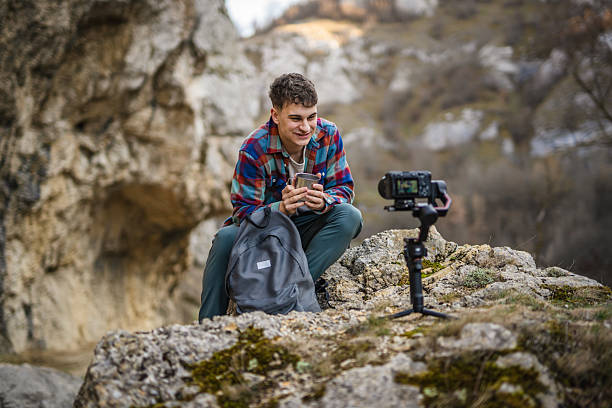 istock Man hiker kneel and making video on camera with stabilizer show cup 2204366019