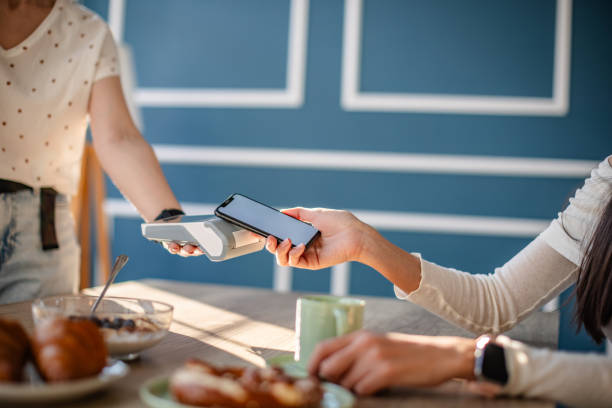 istock Two young adults using mobile technology for contactless payment in a modern restaurant during brunch 2204366310