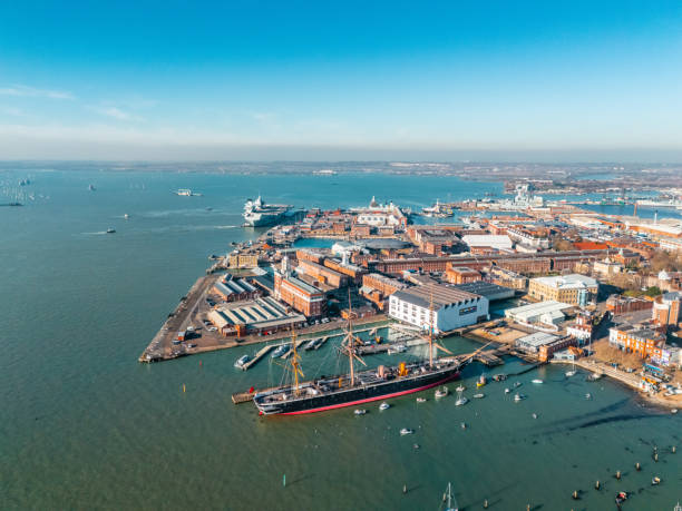 Portsmouth, England - October 31, 2011: Portsmouth Historic Dockyard and Royal Naval Dockyard seen from the top of the Spinnaker Tower. The masts of HMS Warrior are in the foreground; in the middle is HMS Victory, the Royal Navy flagship; to the left is HMS Dauntless, a Type 45 air defence destroyer, preparing for deployment to the Falkland Islands. The circular building near to HMS Victory is the new home of the 'Mary Rose', a warship in Henry VIII's navy which capsized and sank in The Solent in 1545. (Some reflections, distortion and effects of curved and tinted window glass. Shot on a cloudy day with watery sunshine beginning to appear.)
