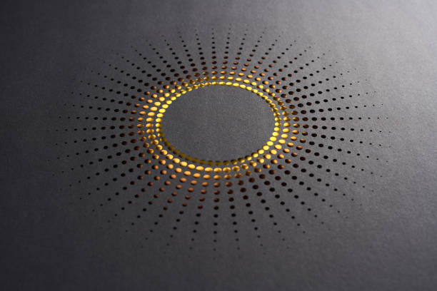 istock Modern paper cutout artwork featuring a sunburst pattern with perforations and glowing golden light on black paper 2204367897