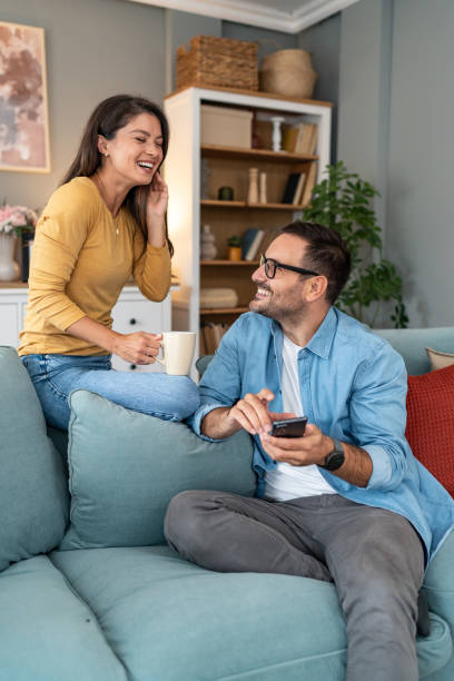 istock Happy couple using phone while relaxing on sofa at home 2204369053