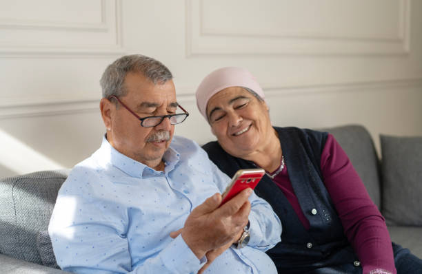 istock Senior couple using mobile phone, home interior 2204369791