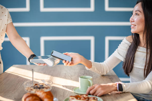 istock Young adults enjoy brunch while using contactless payment technology at a modern restaurant 2204371683