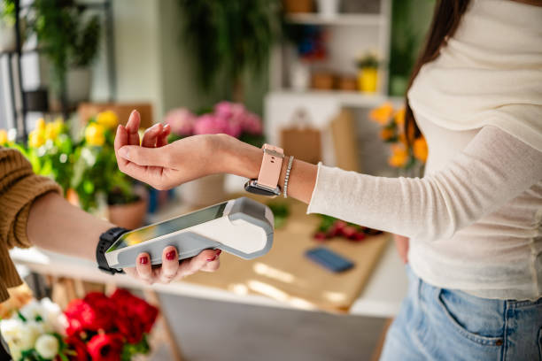 istock Young adults using wireless payment technology at a flower shop checkout to purchase a bouquet of fresh flowers 2204374406