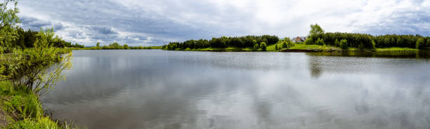 istock Tranquil Waterscape A Serene Lake Nestled Amongst Lush Greenery, All Under a Dreamy Cloudy Sky That Invites Calm and Peacefulness 2204375592
