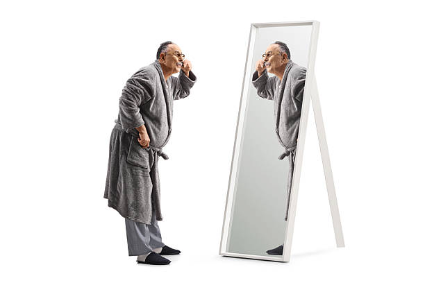 istock Mature man in a bathrobe trimming moustache in front of a mirror 2204376102