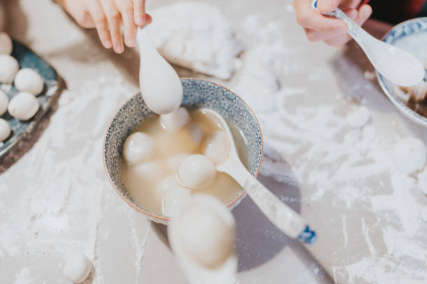 Modern Hong Kong multi-generation family celebrating Chinese New Year. They are eating  glutinous rice balls (dumplings) made by themselves happily
