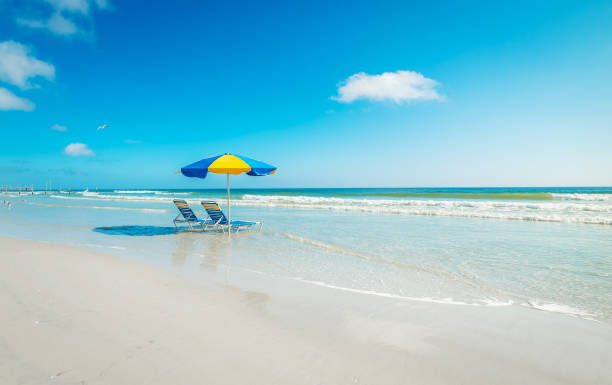 istock Two beach chairs and a colorful parasol on the sand 2204378364