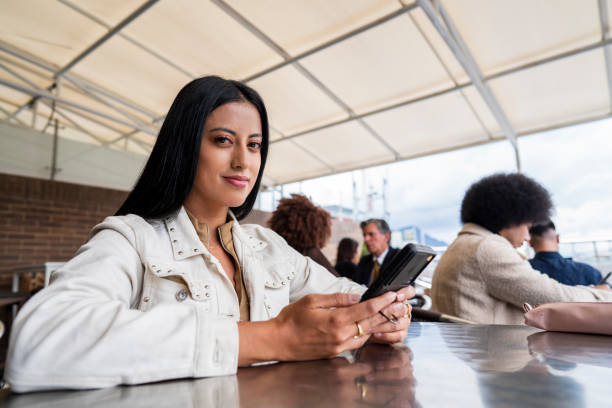 istock Young woman enjoys some quiet time in a restaurant while checking her phone and sharing with some friends 2204385795