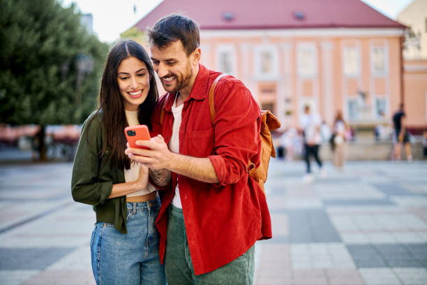 istock Smiling tourists using smartphone and exploring city center 2204387163