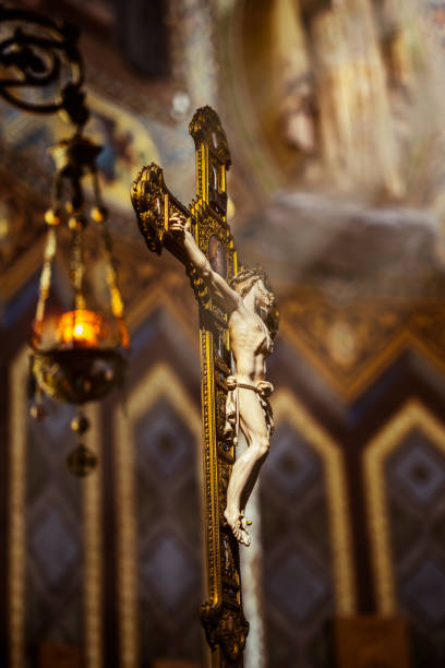 An ornate crucifix featuring Jesus Christ, illuminated by soft light inside a richly decorated church, symbolizing faith, sacrifice, and devotion.