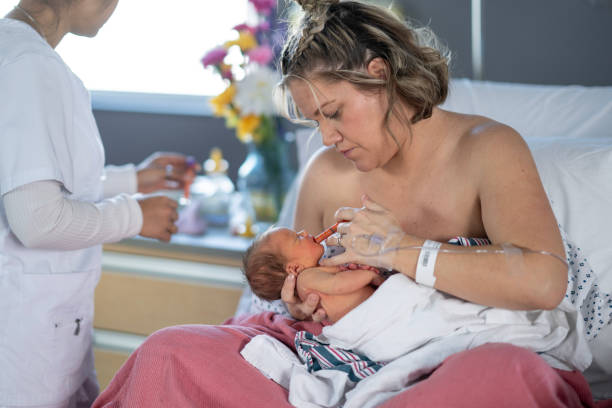 istock Mother Feeding Newborn with Syringe While Nurse Assists 2204388156